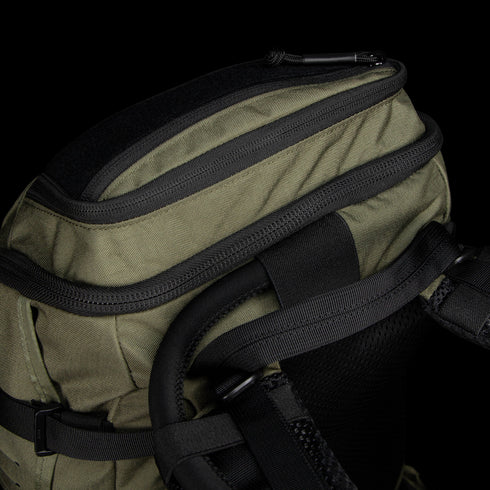 Close-up of the top section of the Condor Nomad Backpack 25L in green, featuring black zippers, straps, and padded shoulder support.